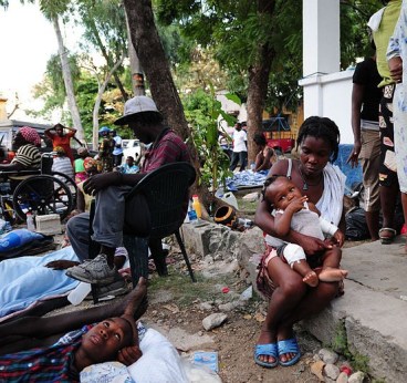 US_Navy_100116-N-2953W-385_A_Haitian_mother_comforts_her_child_at_the_Killick_Haitian_Coast_Guard_Base_clinic_as_a_member_of_the_U.N._security_team_stands_watch